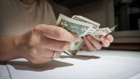 Stressed bankrupt woman counting few money and lying on kitchen table. Concept of financial difficulties, poverty, bankruptcy, taxes and rent payment.の写真素材
