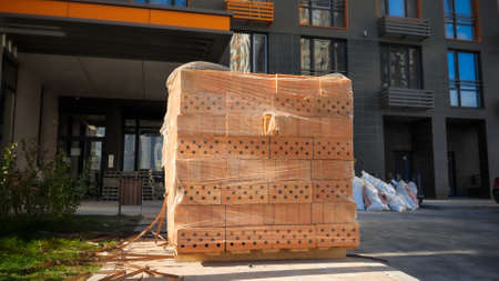 Big stack or red construction bricks on wooden pallet on building siteの写真素材