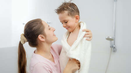 Caring mother drying her son with towel and hugging after bathing. Concept of hygine, children development and fun at homeの写真素材