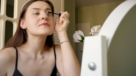 Portrait of elegant woman applying mascara at bedroom makeup table. Skin care, female health and beautyの写真素材