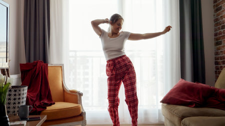 Cheerful smiling woman dancing and having fun in living room. People relaxing at home, having fun, positive emotionsの写真素材