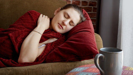 Young sick woman covering in plaid on sofa and coughing. Healthcare, female feeling sick at home,...