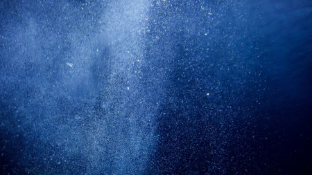 Air bubbles floating and rising up to the sea surface. Sun light shining through ocean. Abstract underwater background or backdrop.の写真素材