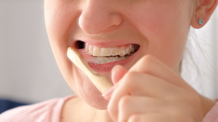 Closeup of young woman opens mouth and cleaning her teeth in the morning. Concept of teeth health,...