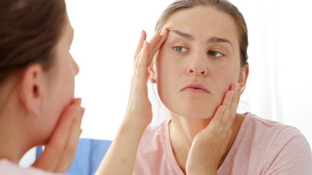 Portrait of young woman pullingher face sking to remove aging wrinkles under eyes.の写真素材