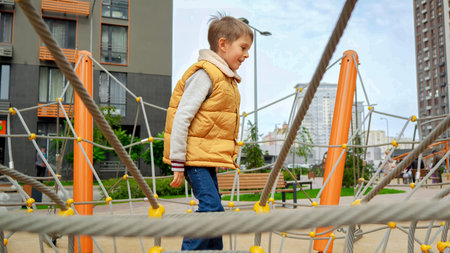 Cheerful smiling boy playing and rocking on the swing with ropes and nets. Active child, sports and...