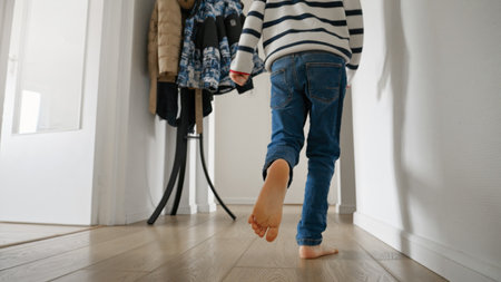 Little boy's feet running on wooden floor in long corridor at home. Concept of happy childhood, playing at home, child developmentの写真素材