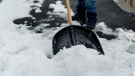 Boy clearing the backyard or walkway from snow after a snowstorm or blizzard. Concept of winter, snow removal, and hard workの写真素材