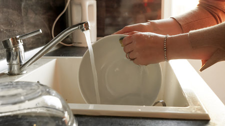 Closeup of woman washing dishes in sink with sponge. Housewife working, domestic chores, doing...