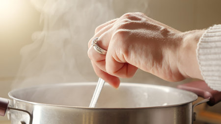 Closeup of young woman cooking soup stirring ingredients in hot water. Healthy nutrition, cooking at home, hot steamの写真素材