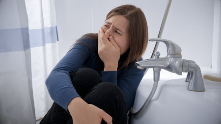Young woman being victim of domestic violence hiding in bathroom and crying. Concept of domestic violence victim, stress, danger at home, fear.の写真素材