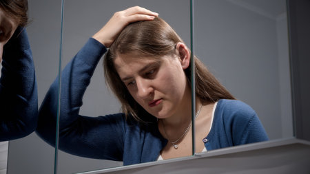 Portrait of angry woman trying to calm down looking in mirror. Concept of depression, stress, mental illness and problems, loneliness and frustrationの写真素材