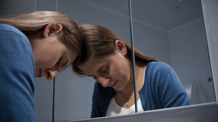 Portrait of angry and stressed woman leaning on mirror and looking in reflection.の写真素材