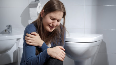Lonely woman suffering from domestic violence crying on floor in toilet. Concept of depression, home violence, suicide, stress, loneliness and frustrationの写真素材