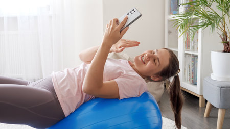Smiling female fitness and healthcare blogger having live translation on social media account during her training. Sports, fitness and yoga bloggers and influencers.の写真素材