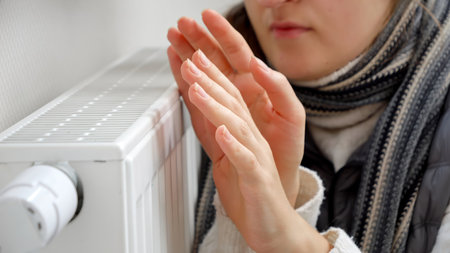 CLoseup of young woman warming her hands next to the radiator or heater at home.の写真素材
