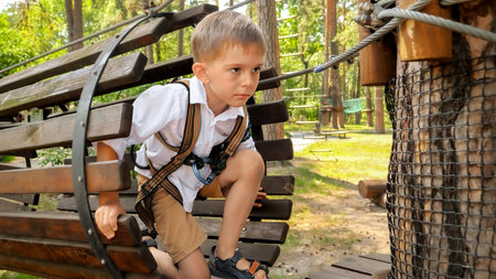 Little boy crawling through tube obstacle in rope adventure park.の写真素材