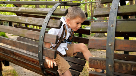 Little boy crawling through wooden pipe or tunnel on playground at park. Active childhood, healthy lifestyle, kids playing outdoors, children in nature.の写真素材