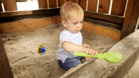 Little boy playing in sandpit with plastic toys and digging sand.の写真素材