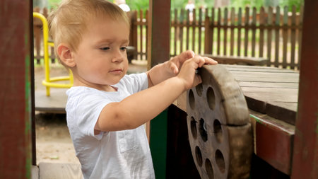 Little baby boy having fun in wooden toy car on the playground. Kids playing outdoors, children having fun, summer vacation and holidayの写真素材