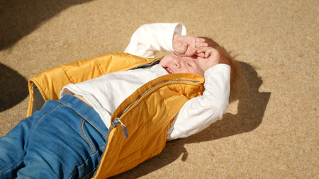 Upset crying and screaming toddler boy lying on ground at playground.の写真素材