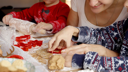 Closeup of little boys rolling dough and making cookies for Santa with mother on kitchen. Winter holidays, celebrations and partyの写真素材