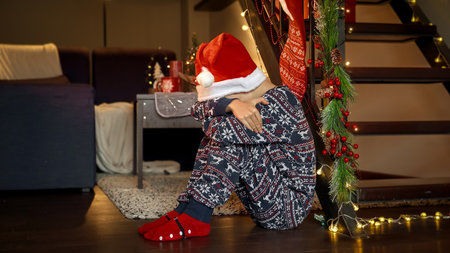 Little upset boy got sad and started crying while waiting for Santa on Christmas eve. Sadness, depression, solitude and negative emotions on winter holidays and New Yearの写真素材