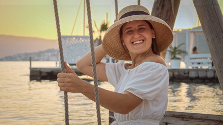 Sea beach with rope swing at sunset. Woman enjoying swinging and swaying. Concept of tourism, summertime, freedom and travelの写真素材