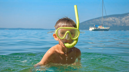 Portrait of little boy wearing diving mask and breathing tube submerging underwater at the sea.の写真素材
