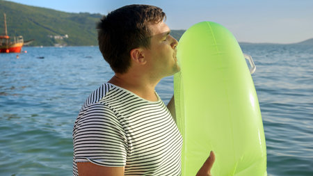 Young father surprises his kids with an inflatable swimming ring on a beach at sunset. Tourism, happiness of summertime, ocean retreats, and family vacations.の写真素材