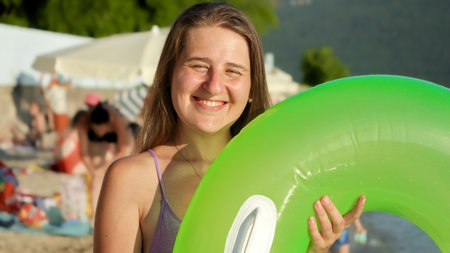 Portrait of happy smiling brunette woman posing with inflatable swimming ring on sea beach.の写真素材