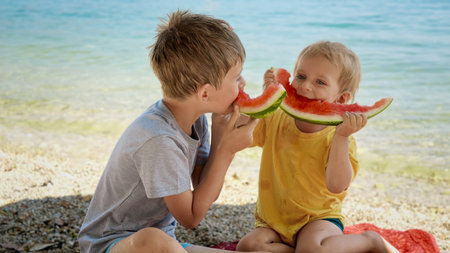 Two funny boys sitting on the beach and having fun with watermelon rinds after eating at the seaの写真素材