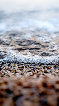 Macro abstract shot of foam, calm sea waves and small rocks on a sea beach.の写真素材