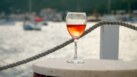 Closeup of wine glass on bar table against sea waves and pierの写真素材