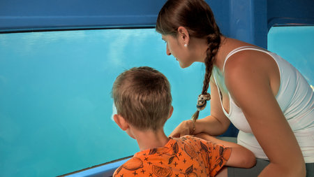 Happy boy with young mother having a tourist trip on submarine and looking on fishes through window. Holiday, summer vacation and tourism.の写真素材