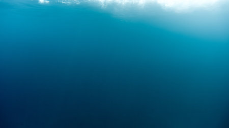 Abstract blurred underwater background of light rays shining through waves and clear sea water.の写真素材