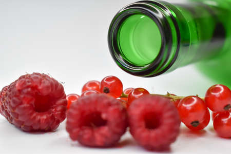 Fresh raspberries and currants with a green bottle.の写真素材