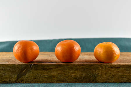 Three mandarins on a wooden board.の写真素材