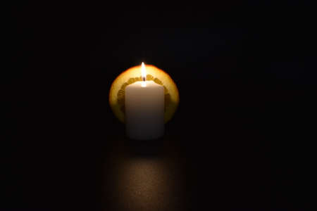 Candle in a dark room with a lighted candle in the middleの写真素材