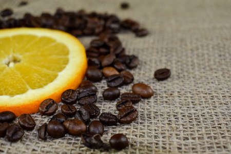 Coffee beans and orange on burlap background. Selective focus.の写真素材