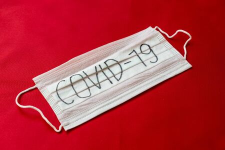 Medical mask with the inscription Covid-19 on a red backgroundの写真素材