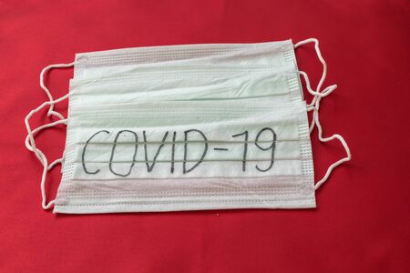 Medical mask with the inscription Covid-19 on a red backgroundの写真素材