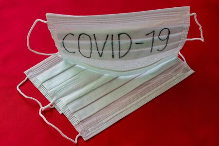 Medical mask with the inscription Covid-19 on a red backgroundの写真素材