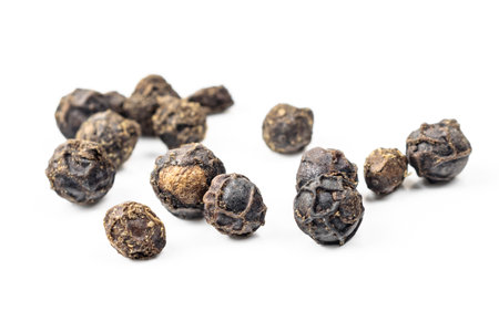 black peppercorns with a visible texture on a white backgroundの写真素材
