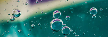 oil drops on water on blue and yellow backgroundの写真素材