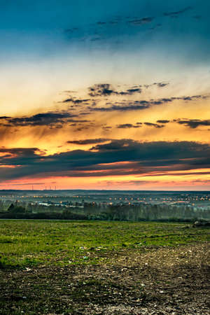 the colorful sunset over the fields with the village visible in the backgroundの写真素材