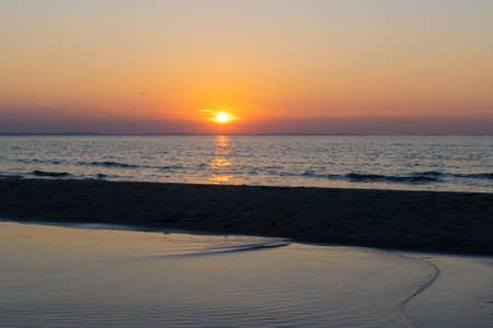 the setting sun against the backdrop of a calm seaの写真素材
