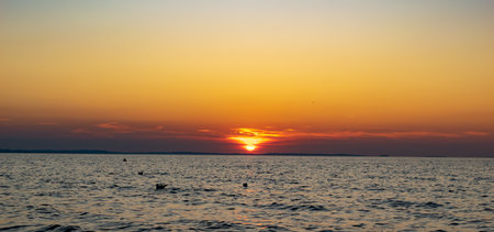the setting sun against the backdrop of a calm seaの写真素材