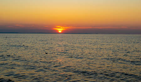 the setting sun against the backdrop of a calm seaの写真素材