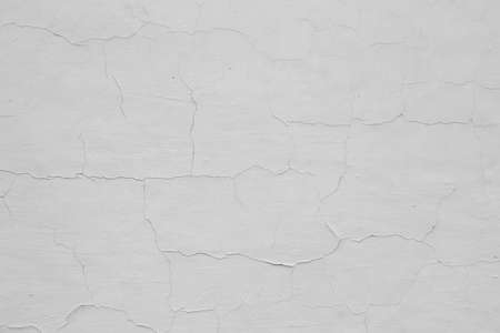 the wall is painted with white paint with visible cracksの写真素材